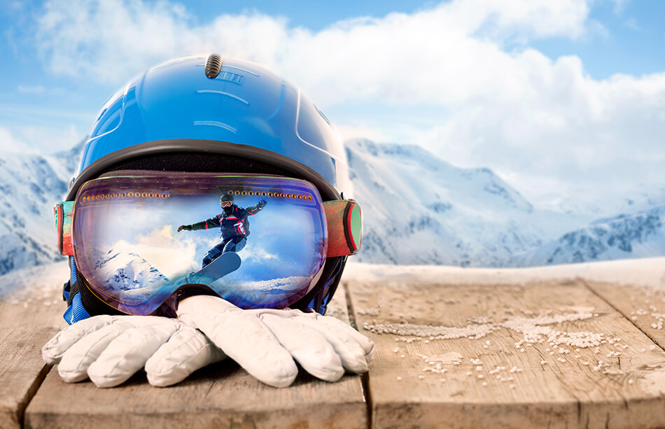 sports goggles, helmet and winter gloves with mountains in the background